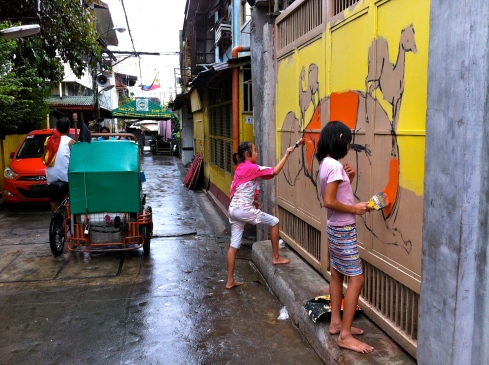 Young collaborators from Bahay Tuluyan painting in torrential rain